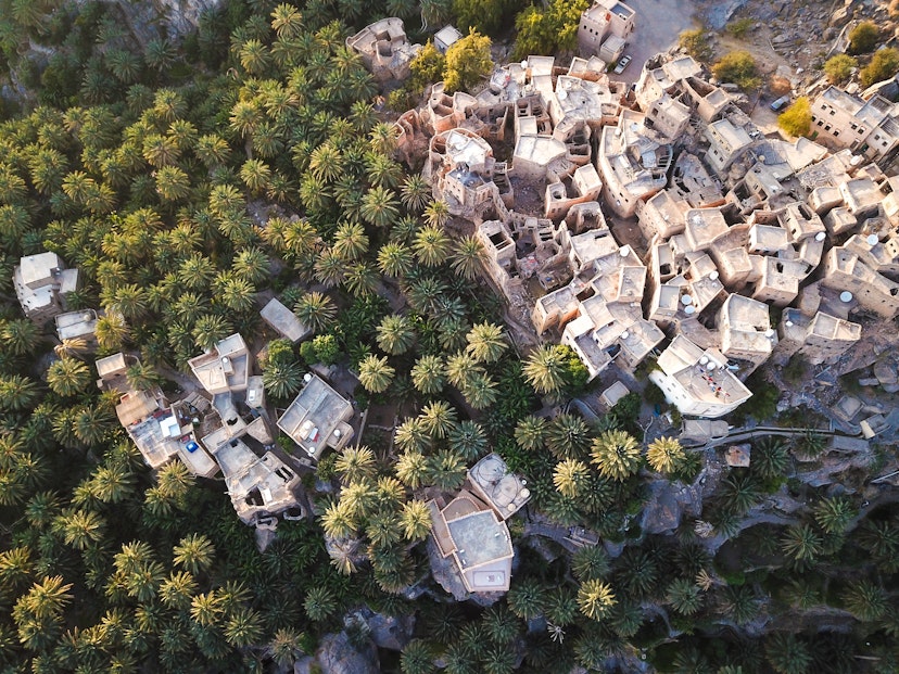 Aerial of an old traditional Omani mud village (Misfat Al Aberyeen) in the mountains among date palm trees.