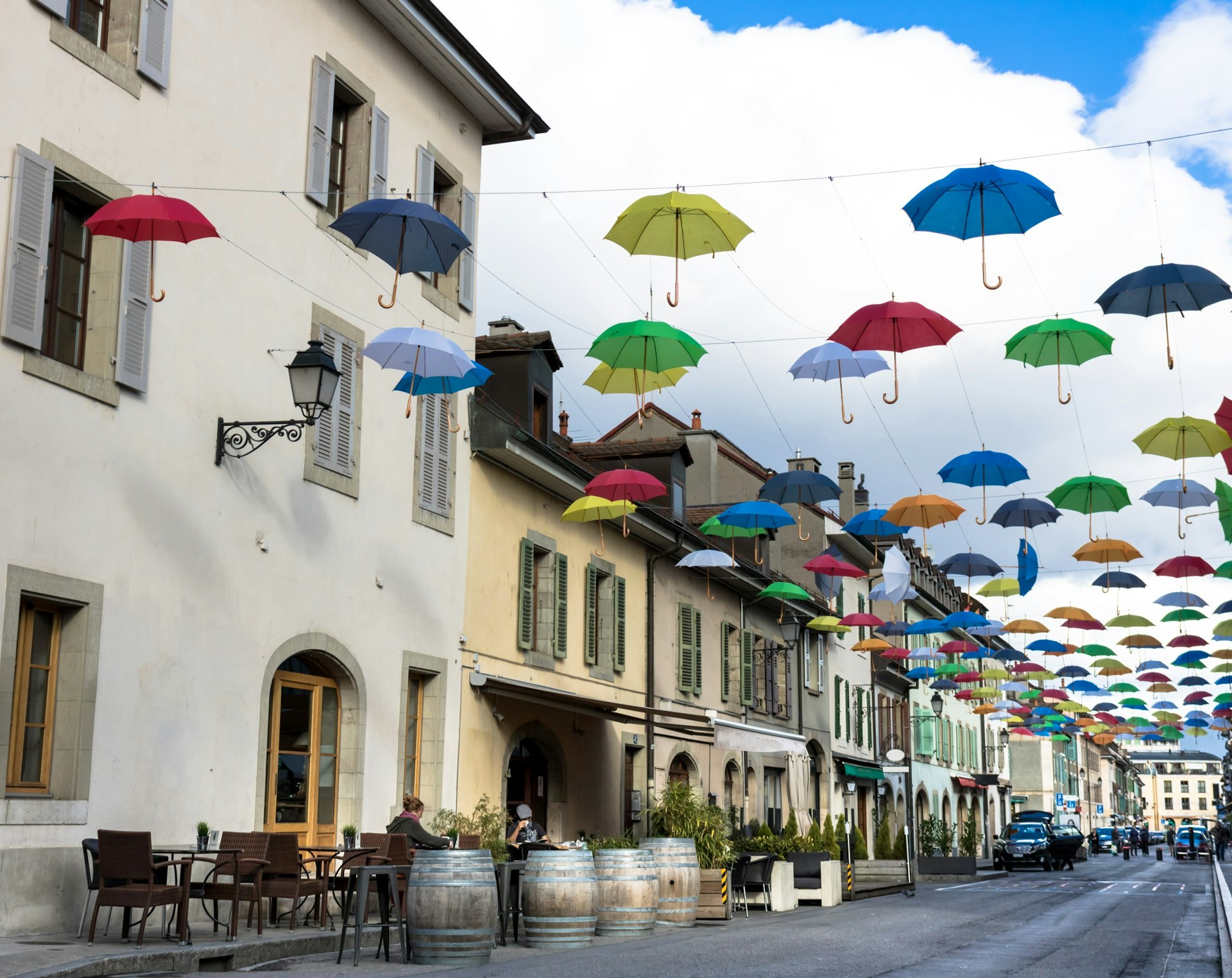 Multicolored umbrellas hang from wires above the street in the Carouge area, Geneva.