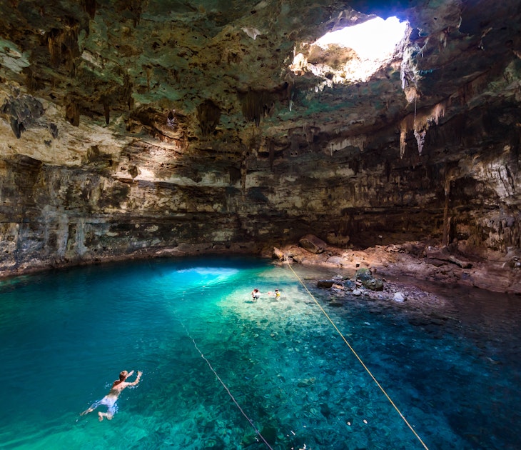 People swimming in crystal blue water at Cenote Samula Dzitnup near Valladolid.