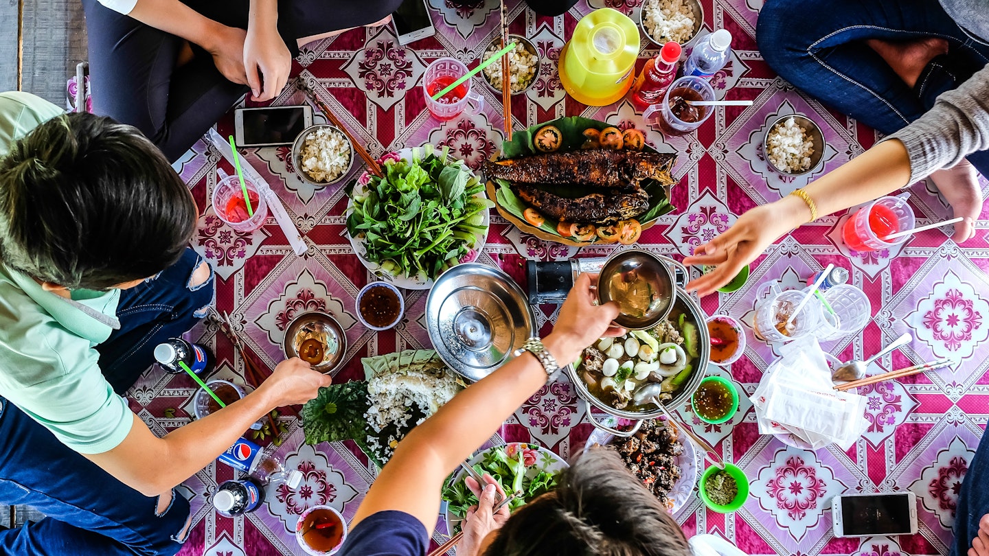 DONG THAP / VIETNAM, 30 DECEMBER 2017 - Top view of happy friends at picnic on countryside outdoor , having lunch with traditional foods.