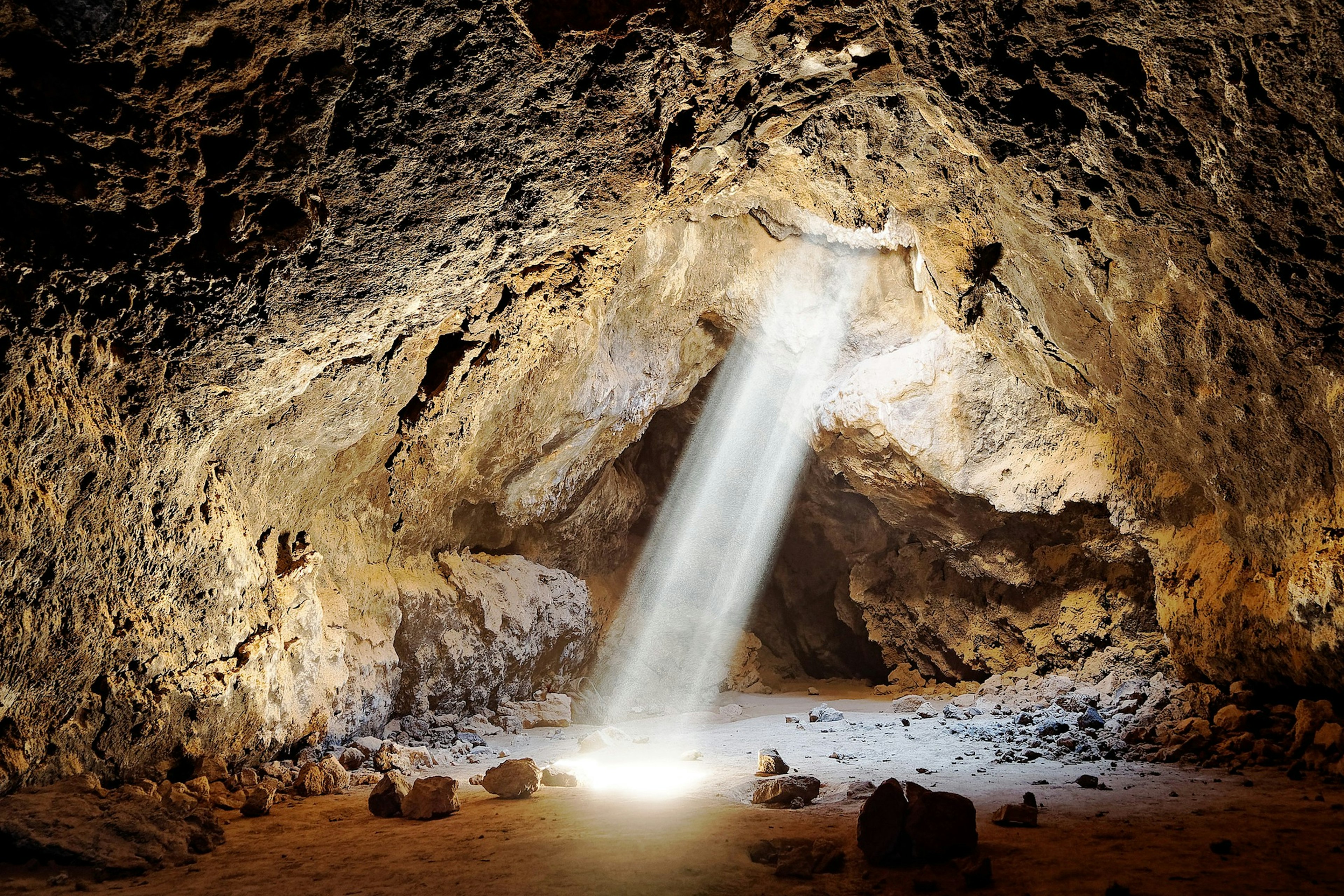 A column of light shines down into a lava tube in Mojave National Preserve, which hints at the dramatic geologic forces that shaped this corner of California