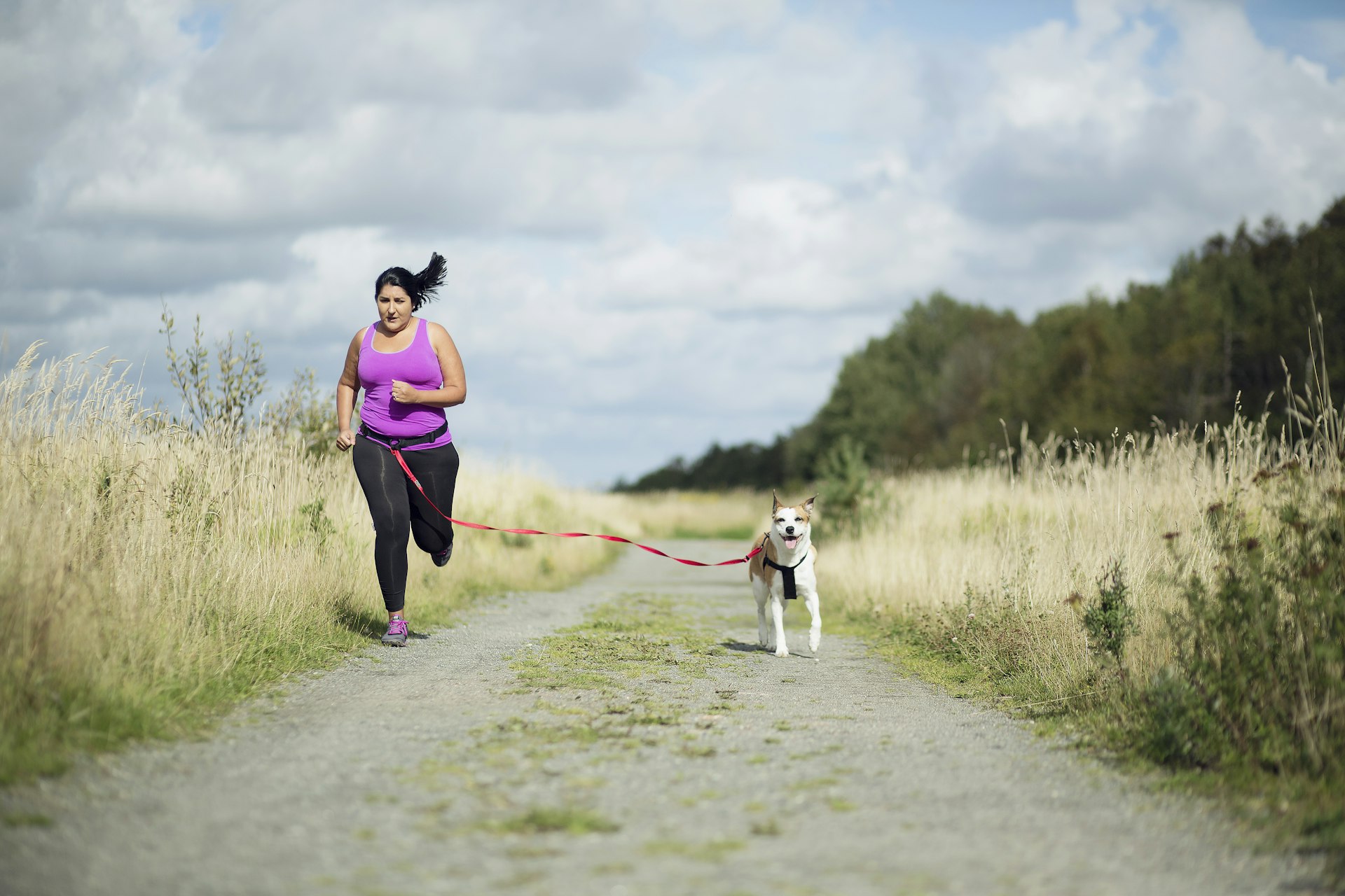 Female jogger running with dog on leash