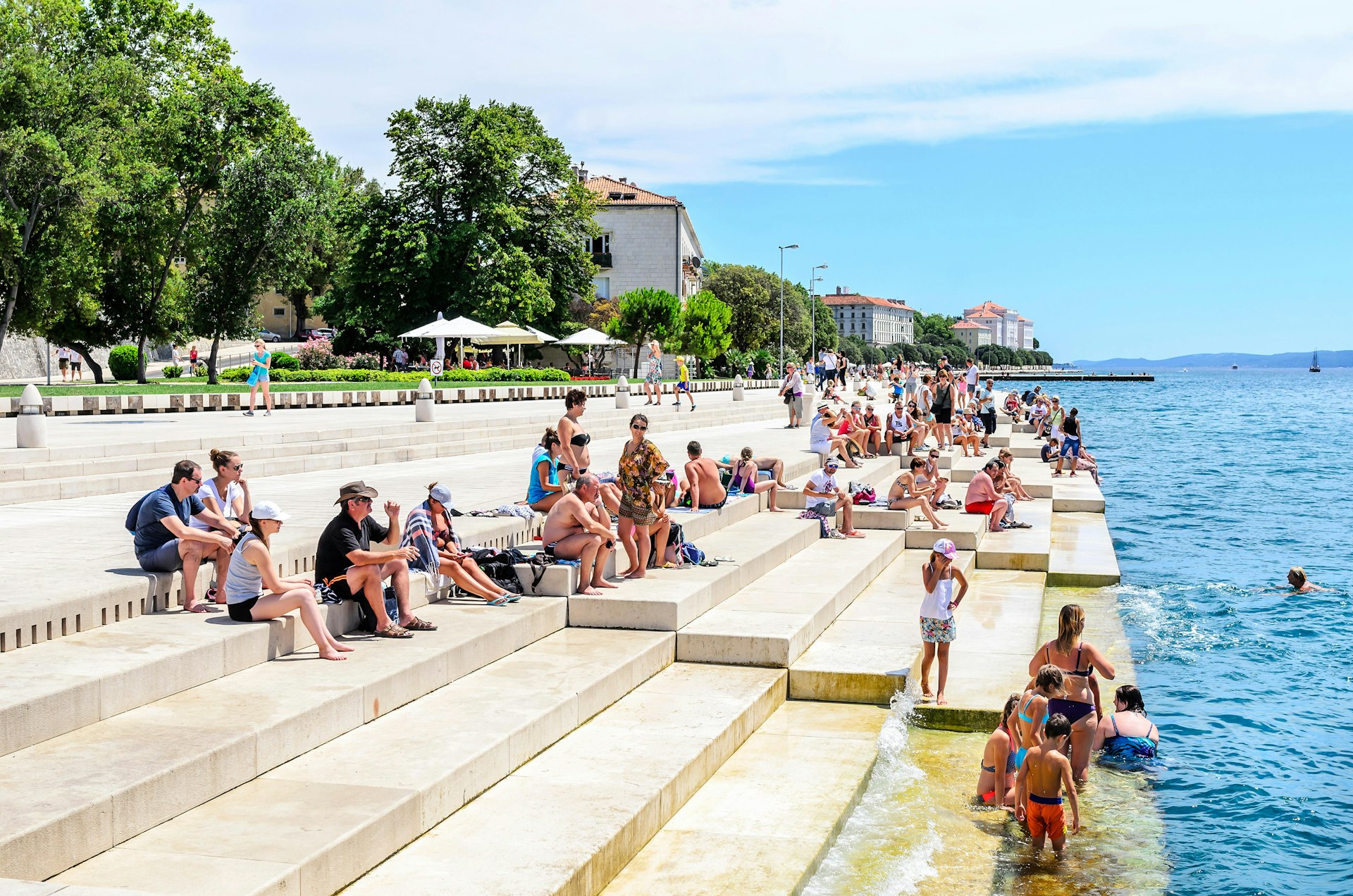 People sitting on the steps near the sea organ in Croatia