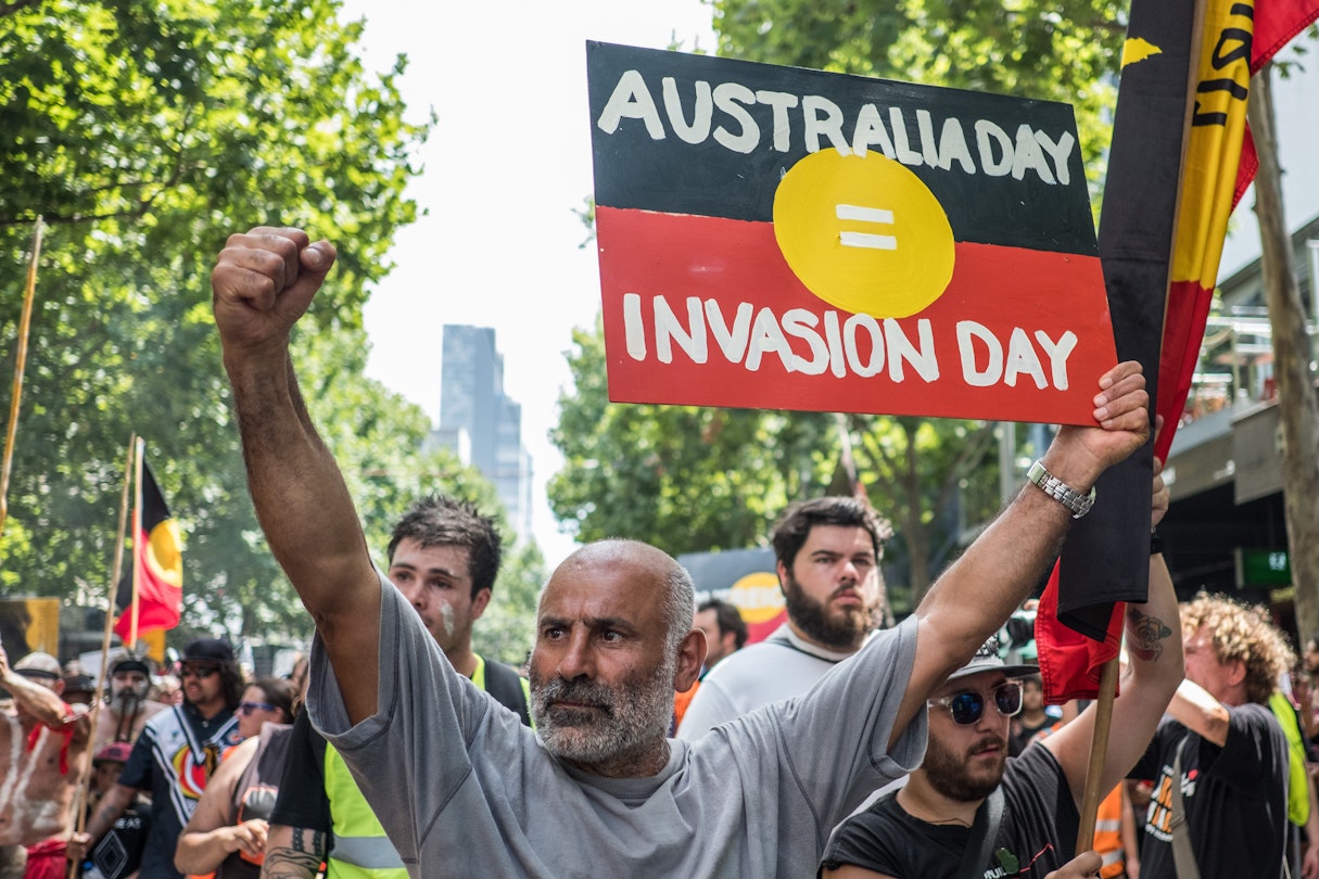 MELBOURNE, AUSTRALIA - JANUARY 26 : A protestor holding a placard reading 'Australia day = Invasion Day' during a protest by Aboriginal rights activist on Australia Day in Melbourne, Australia 26 January 2018. Australia Day is named by some as Invasion Day due to the dispossession of Indigenous land and the arrival of the First Fleet's at Port Jackson, Sydney, in 1788. (Photo by Asanka Brendon Ratnayake/Anadolu Agency/Getty Images)