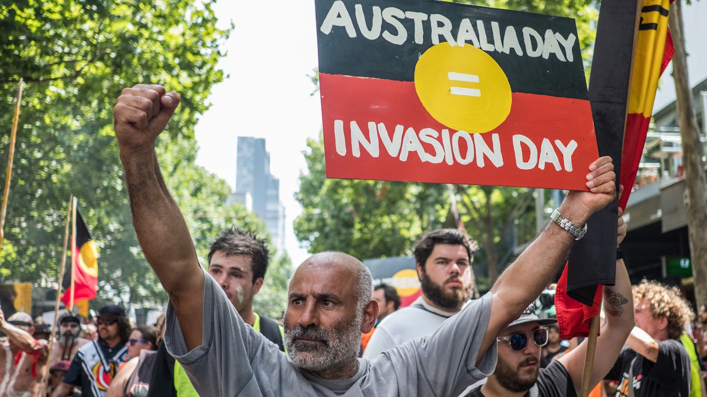 MELBOURNE, AUSTRALIA - JANUARY 26 : A protestor holding a placard reading 'Australia day = Invasion Day' during a protest by Aboriginal rights activist on Australia Day in Melbourne, Australia 26 January 2018. Australia Day is named by some as Invasion Day due to the dispossession of Indigenous land and the arrival of the First Fleet's at Port Jackson, Sydney, in 1788. (Photo by Asanka Brendon Ratnayake/Anadolu Agency/Getty Images)