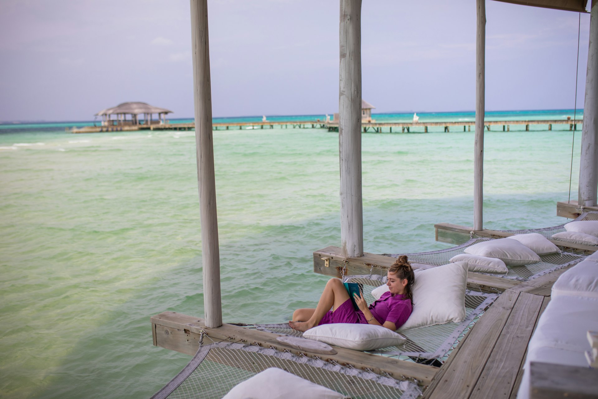 Woman reading a book on the veranda of an overwater bungalow in the Maldives
