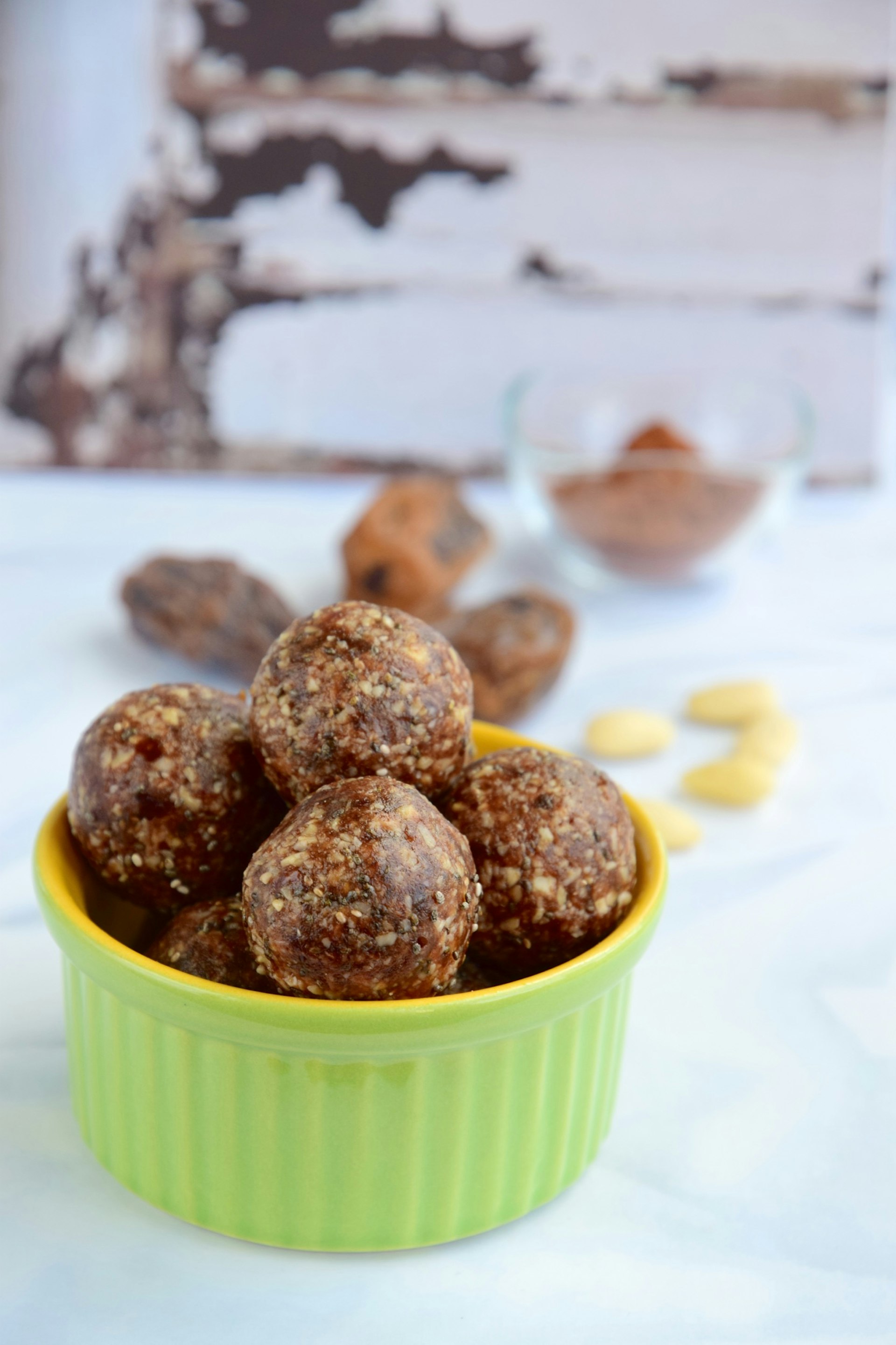 Date almond oat chocolate energy balls in a lime green bowl 