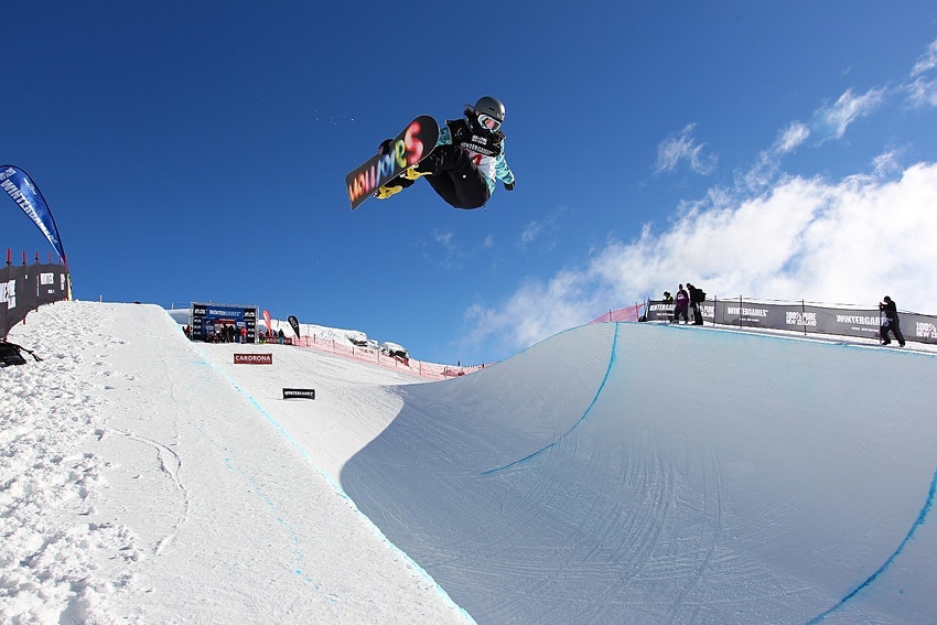 Snowboarder sails above a halfpipe at Cardrona
