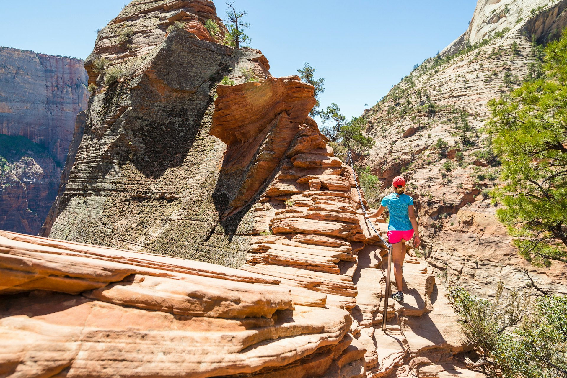 Young woman is walking along the ridge in beautiful scenery in Zion National Park along the Angel's Landing trail, Hiking in Zion Canyon, Utah, USA.