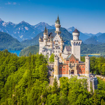 Fussen, Germany - August 7, 2015: Beautiful view of world-famous Neuschwanstein Castle, the nineteenth-century Romanesque Revival palace built for King Ludwig II on a rugged cliff, with scenic mountain landscape near Fussen, southwest Bavaria, Germany.