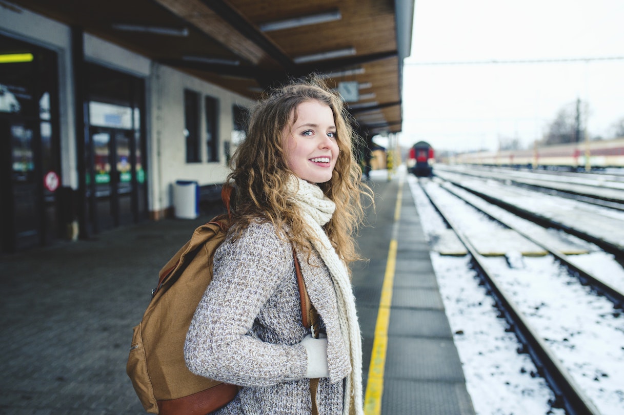 Smiling teenage girl on a train station platform during winter.