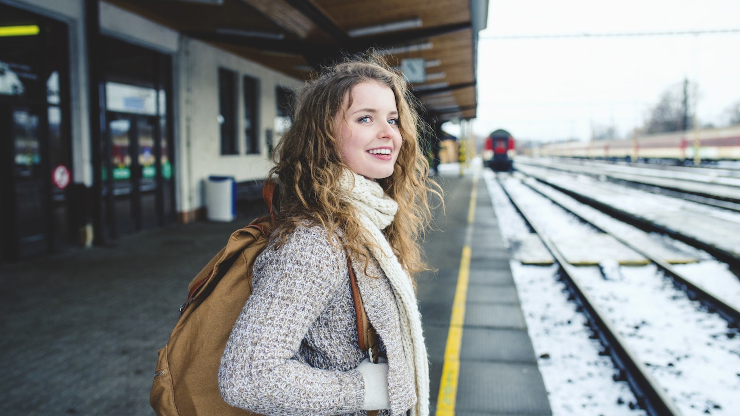 Smiling teenage girl on a train station platform during winter.
