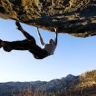 Woman bouldering on an overhang at the Buttermilk Boulders near Bishop California..