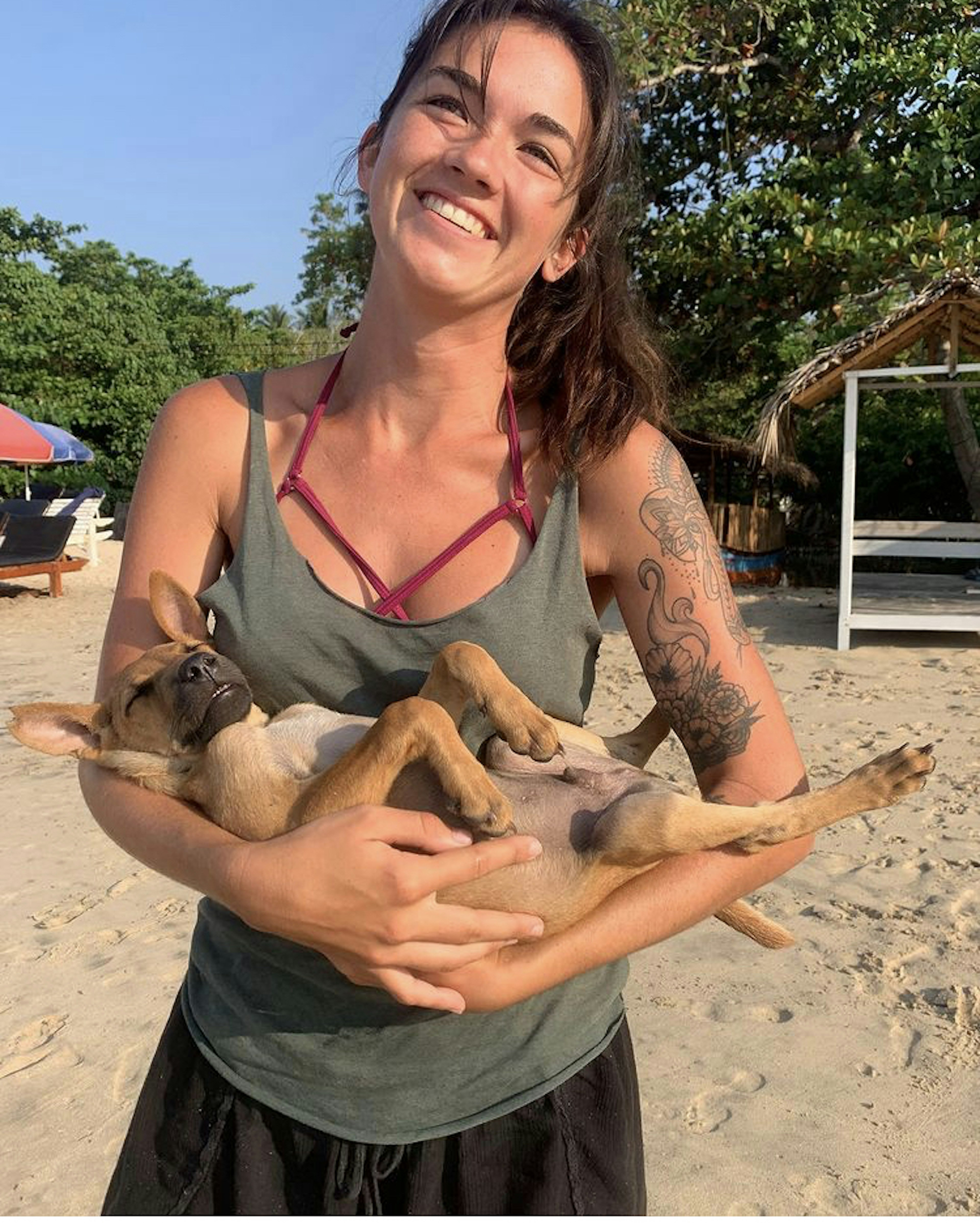 A white woman holding a puppy smiles at the camera