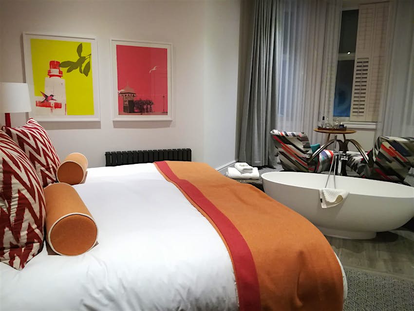 Interior shot of a hotel room, mainly white, with flashes of bright orange stripy decor