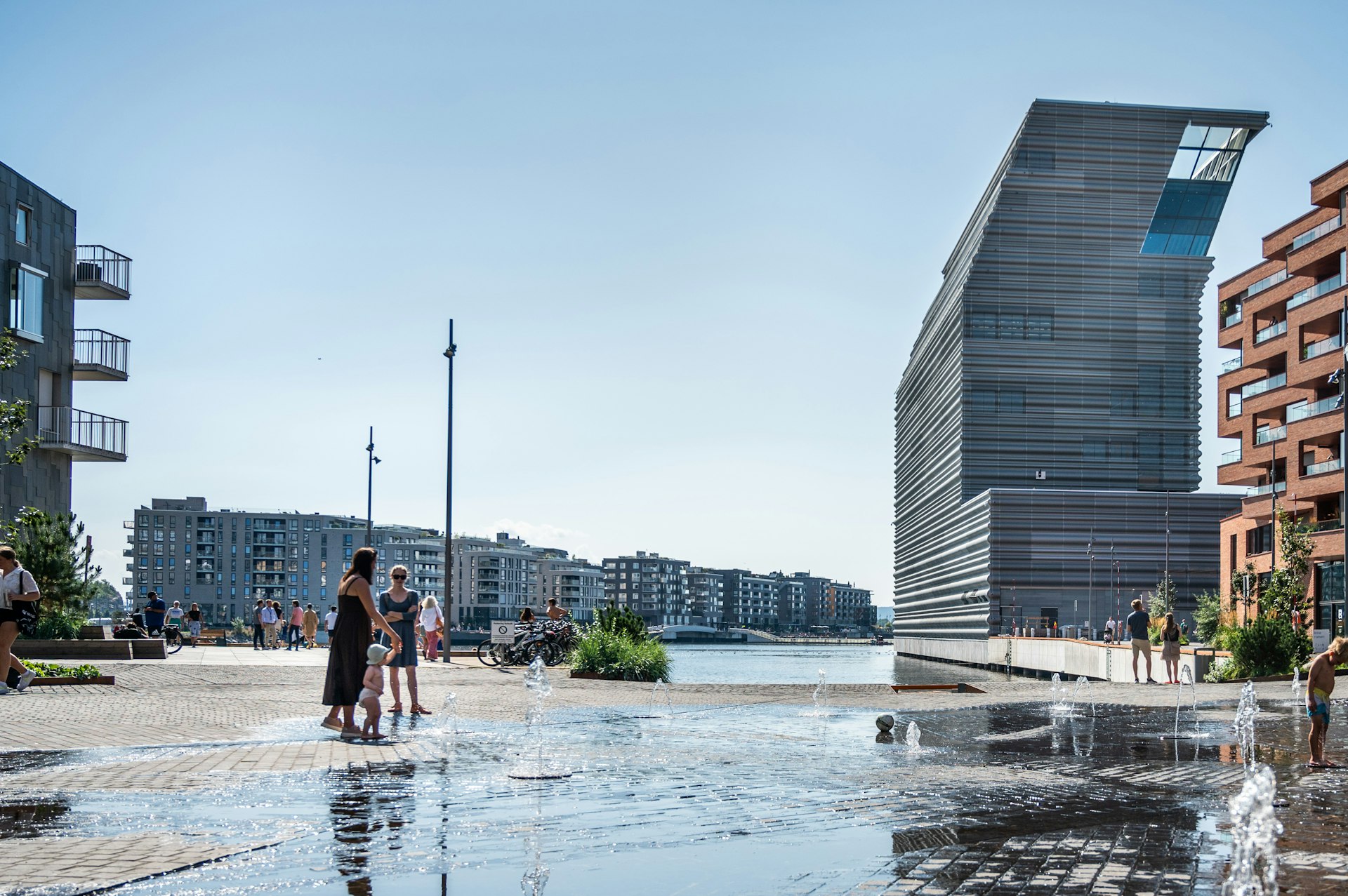 Exterior shot of Oslo's new waterfront Munch museum with people wading in the water