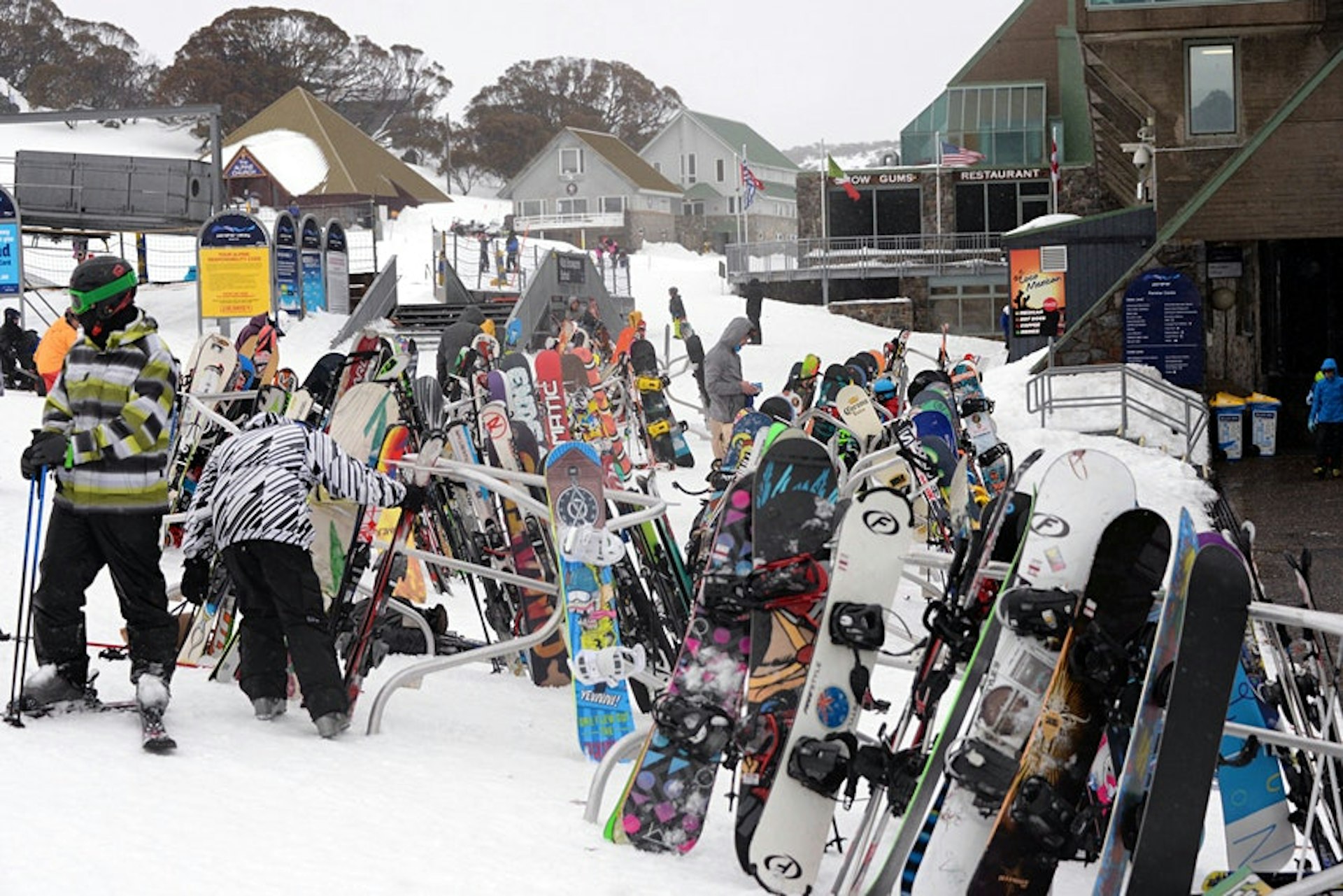 Snowboarders and skiers post their skis and snowboards on railings outside a snow resort in Australia. 