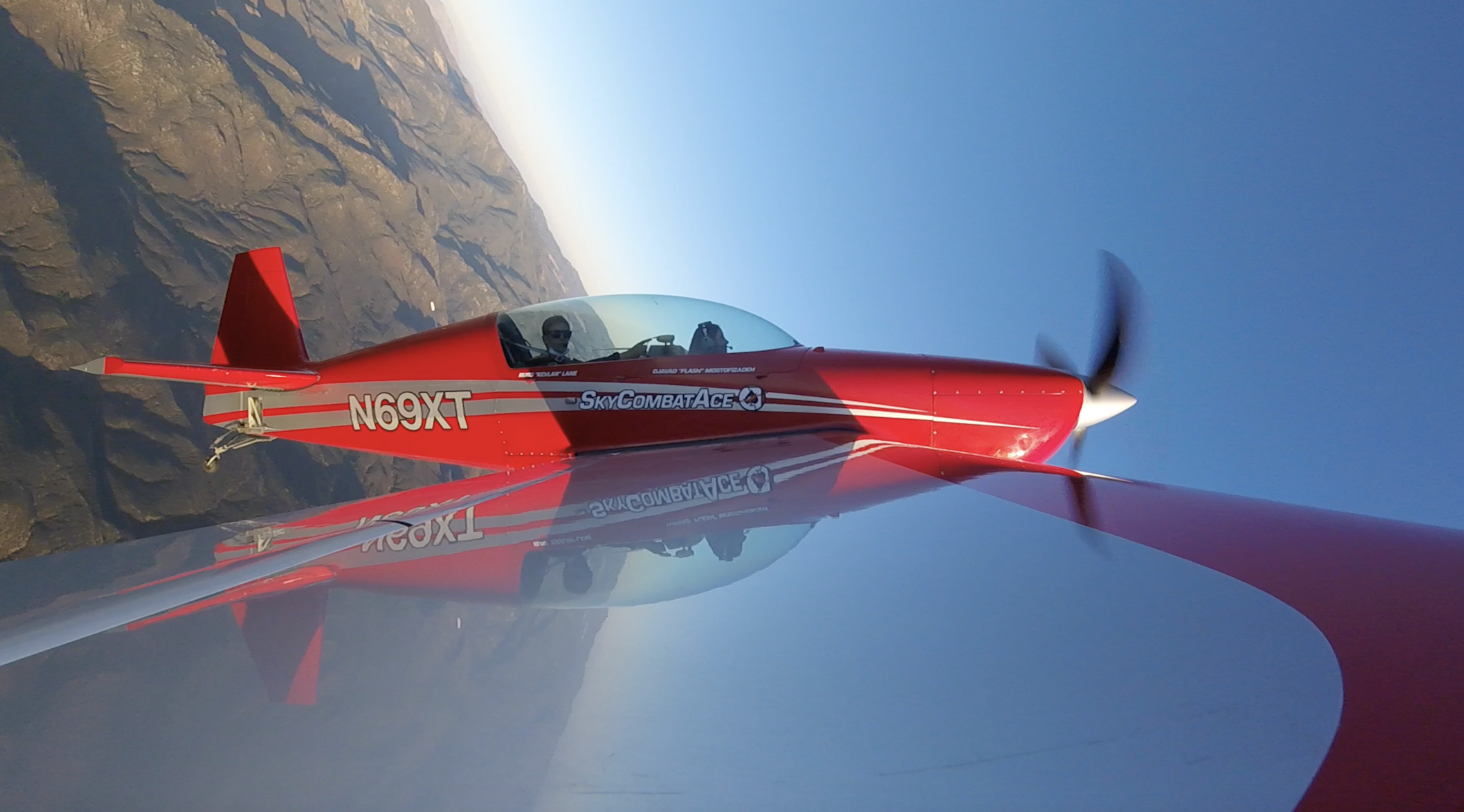 A view from the wing of a small red plane in the air
