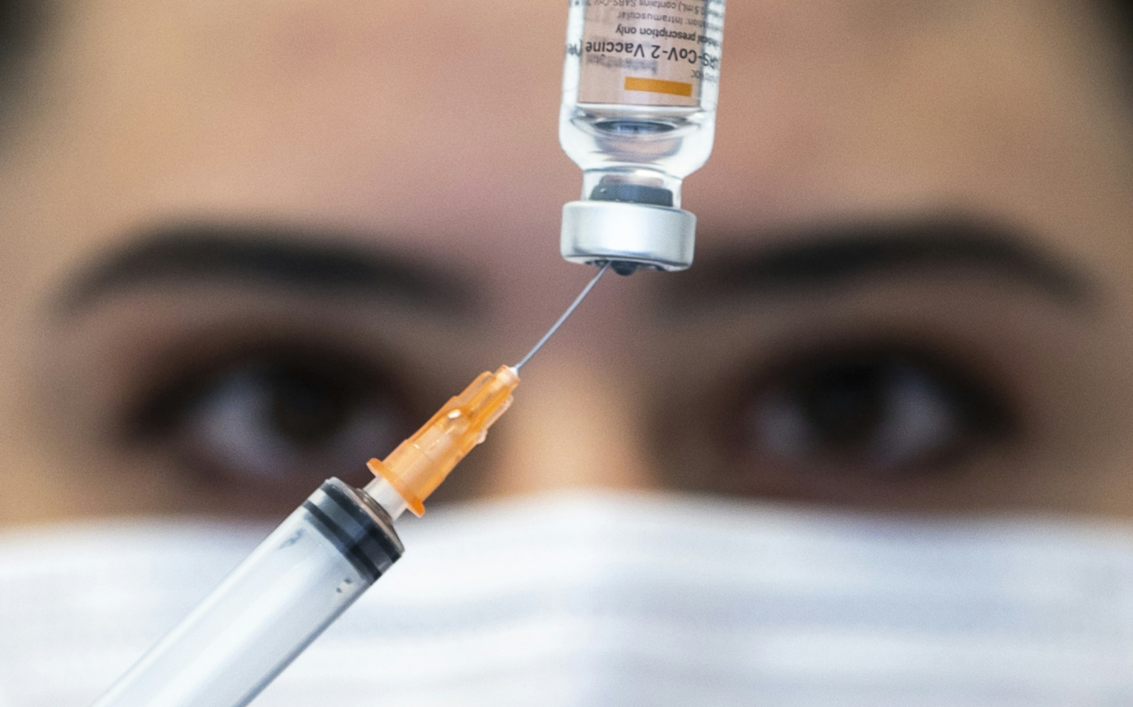 Eyes behind a vial of Covid-19 vaccination