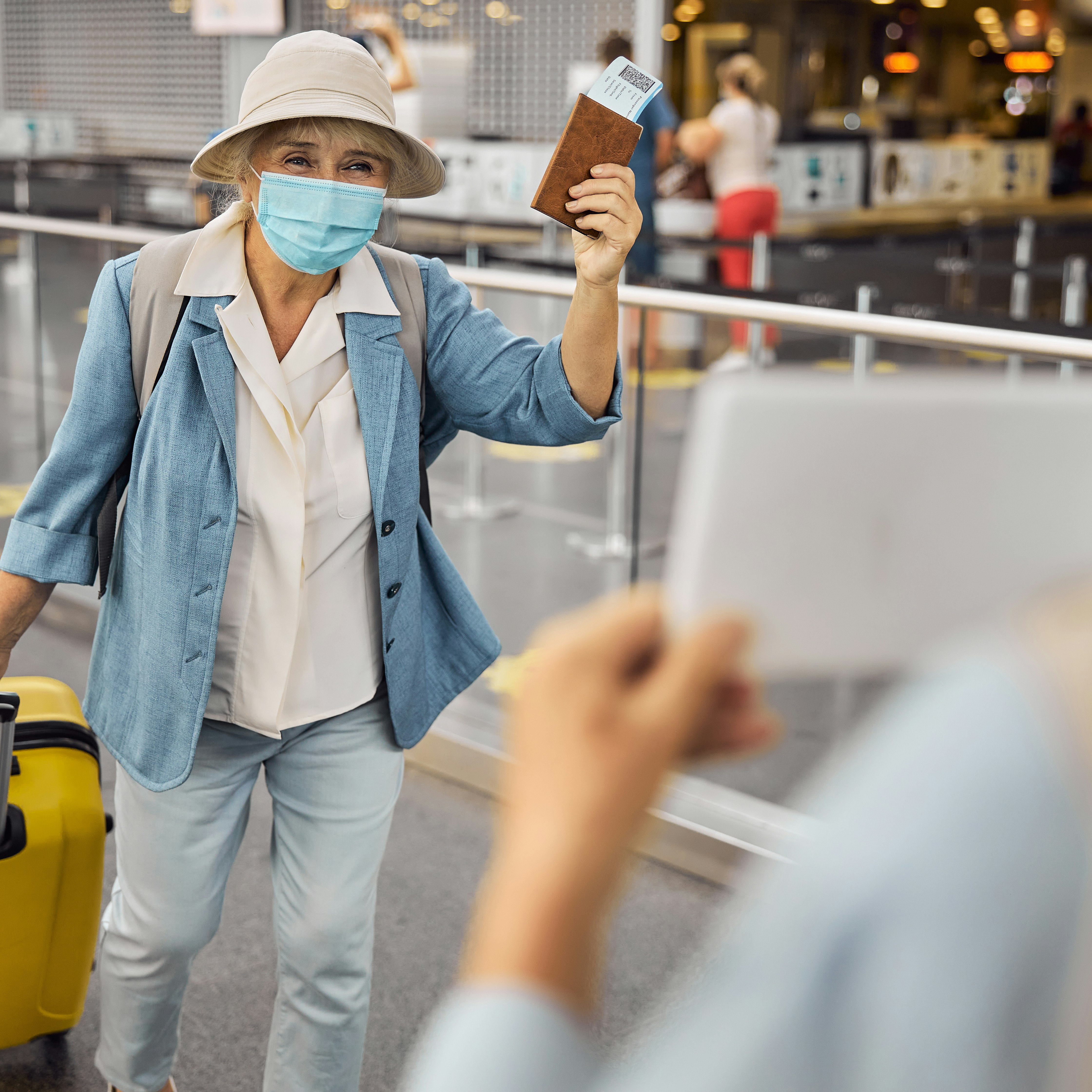 Newly arrived female passenger in a face mask walking towards a man with a sign