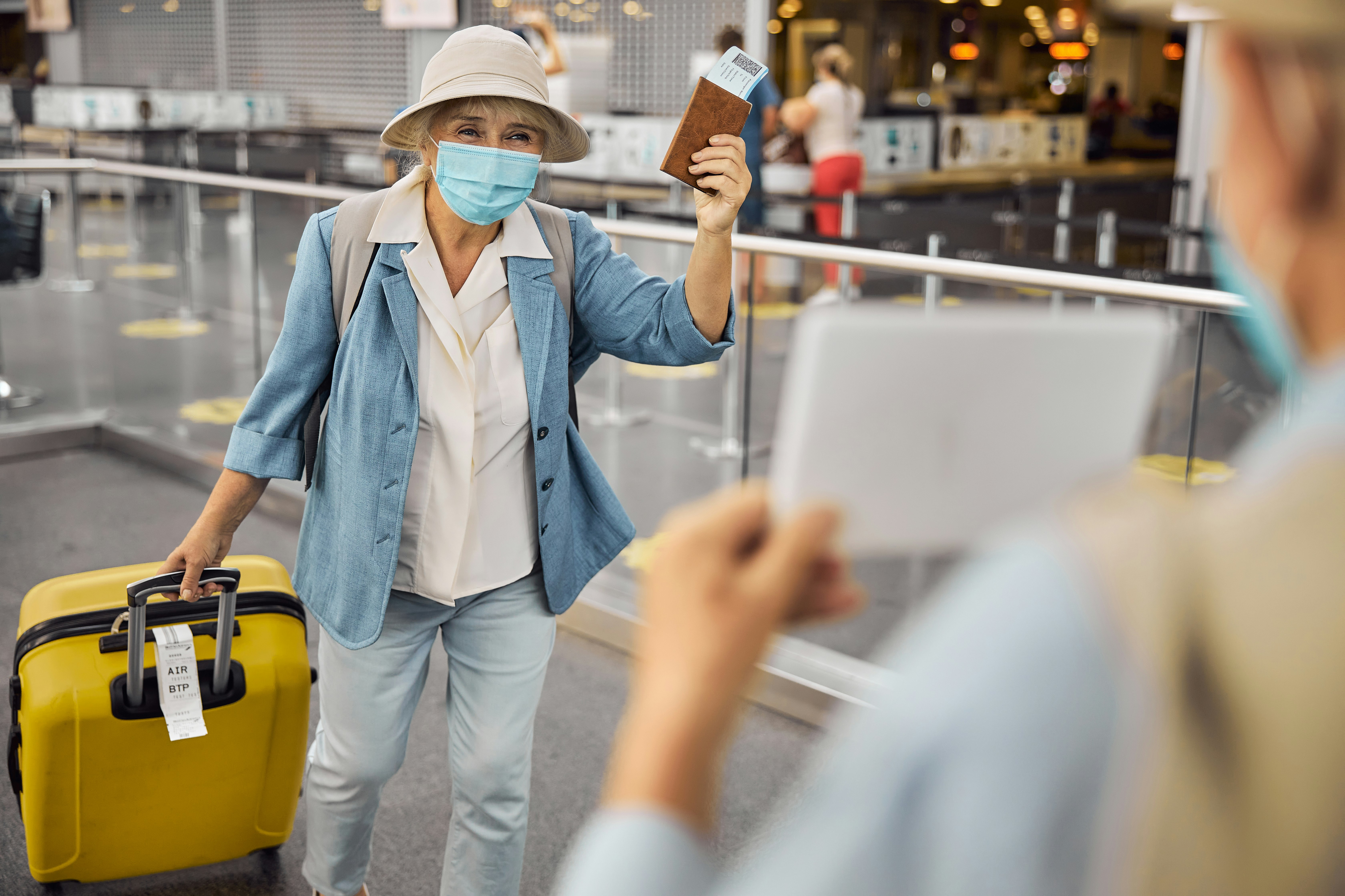 Newly arrived female passenger in a face mask walking towards a man with a sign