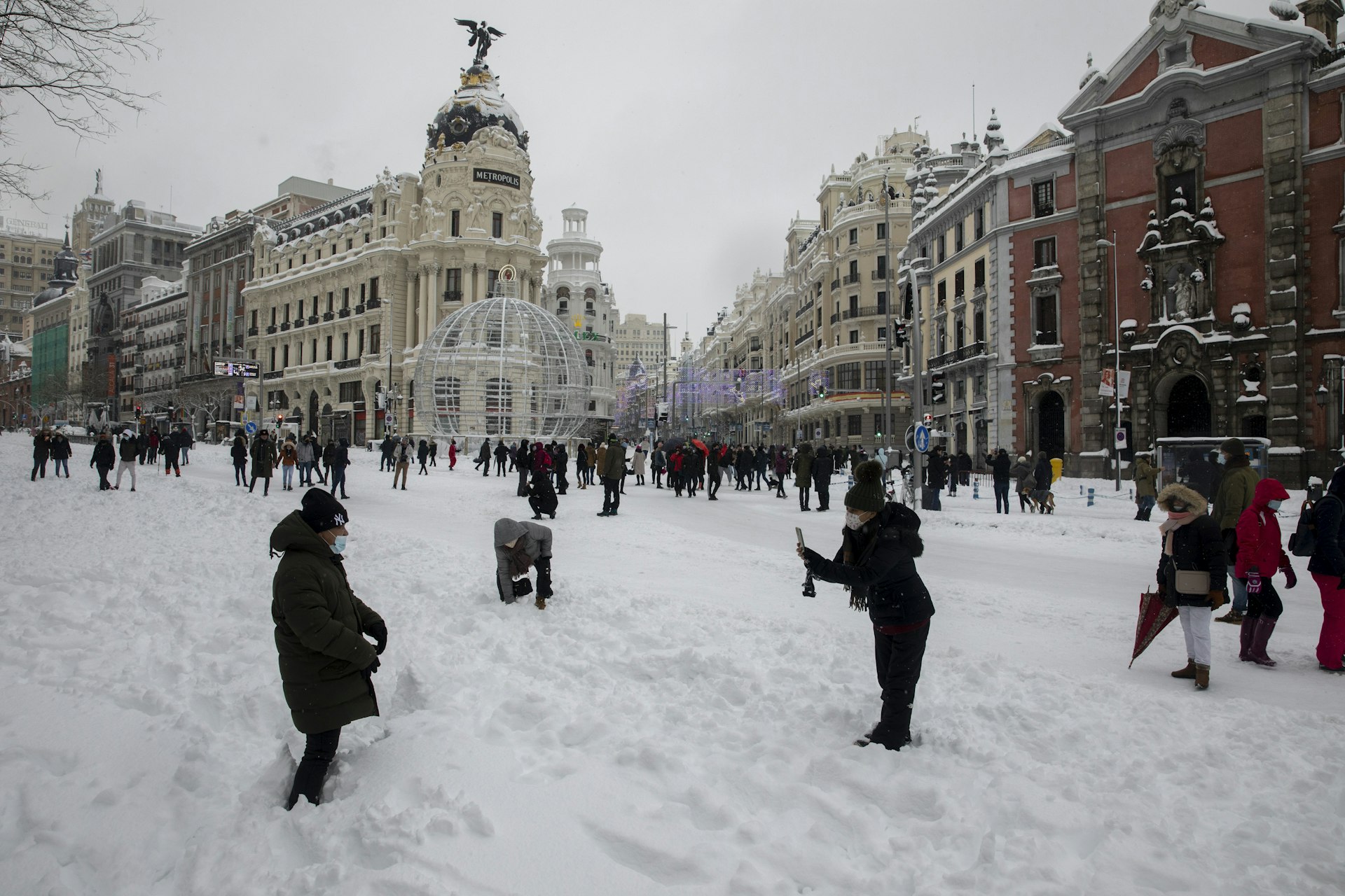 People gathering in Madrid's Calle Alcalá to experience the snow