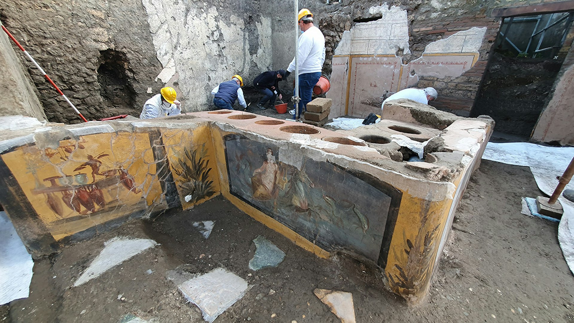 Archaeologists study frescoes at an ancient snack bar in Pompeii