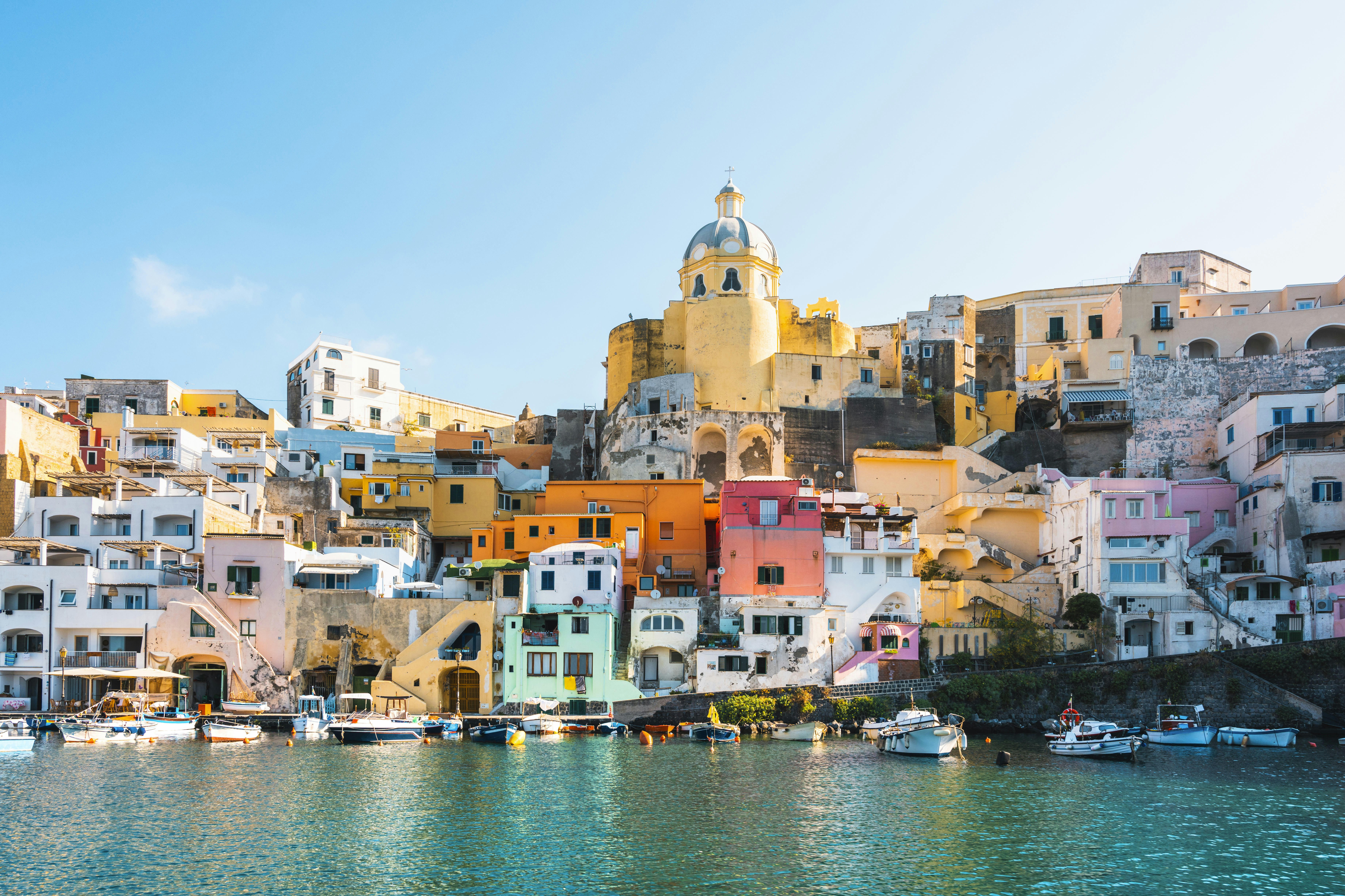 The vibrantly colored buildings of the port of Procida, seen from the water