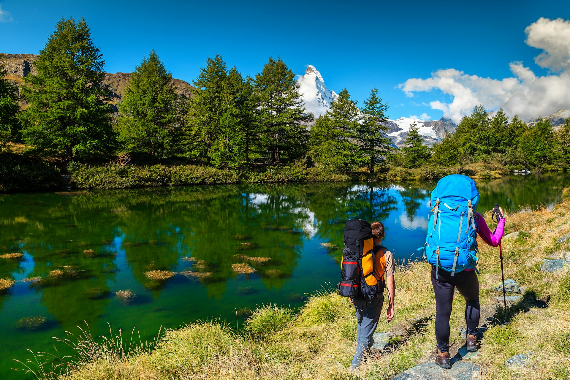 Two hikers with backpacks near the Grindjisee alpine lake in Zermatt