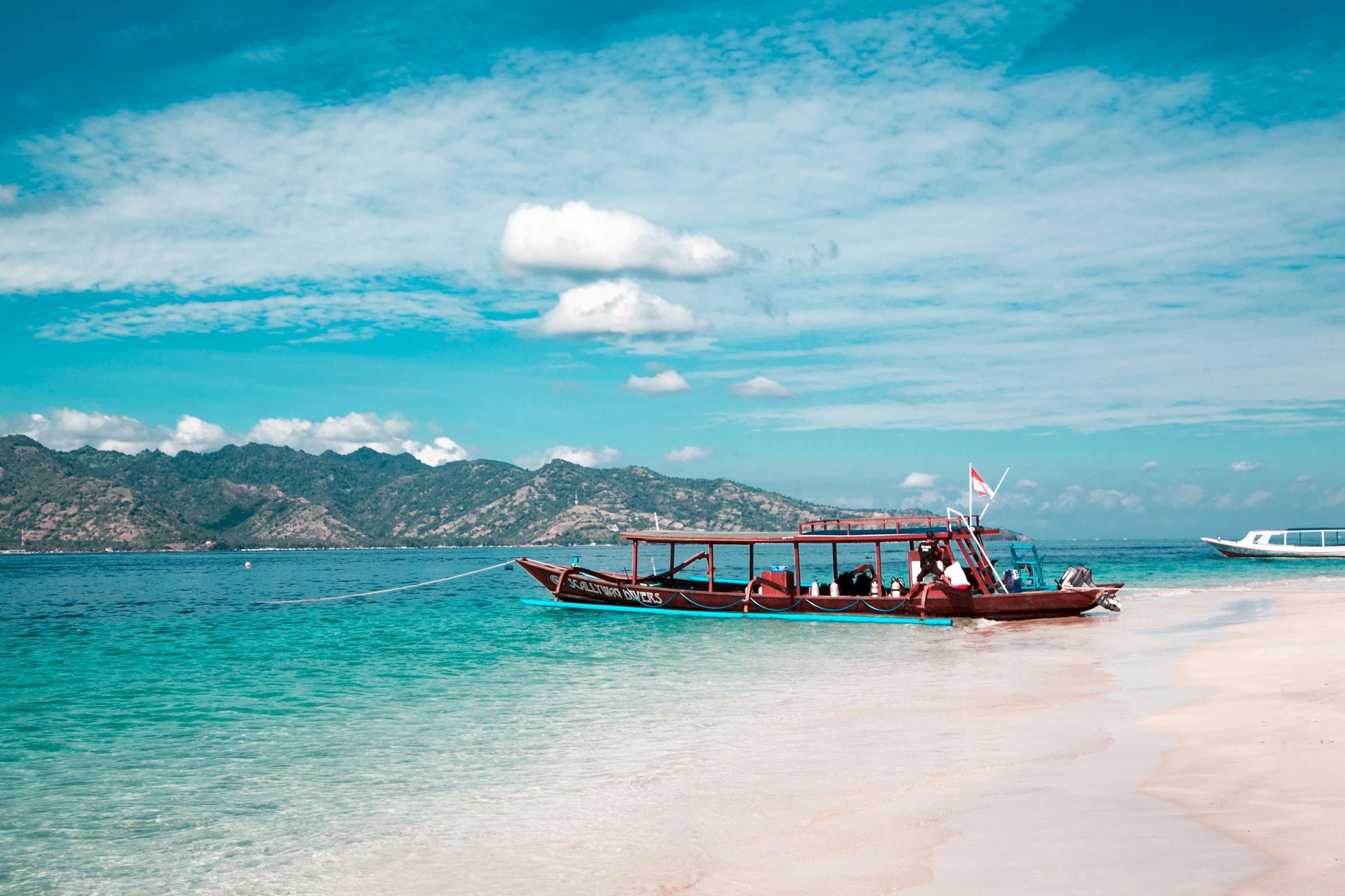 A red dive boat on the beach with cannisters lined up along the side