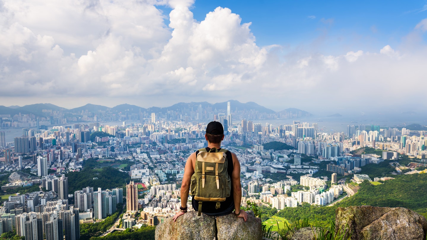 Man sitting on Lion Rock lookout with the city of Hong Kong below.