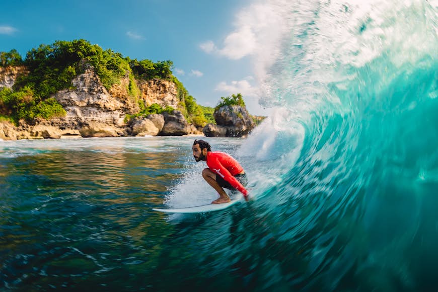 Surfer naik dalam gelombang barel.  Bali, Indonesia