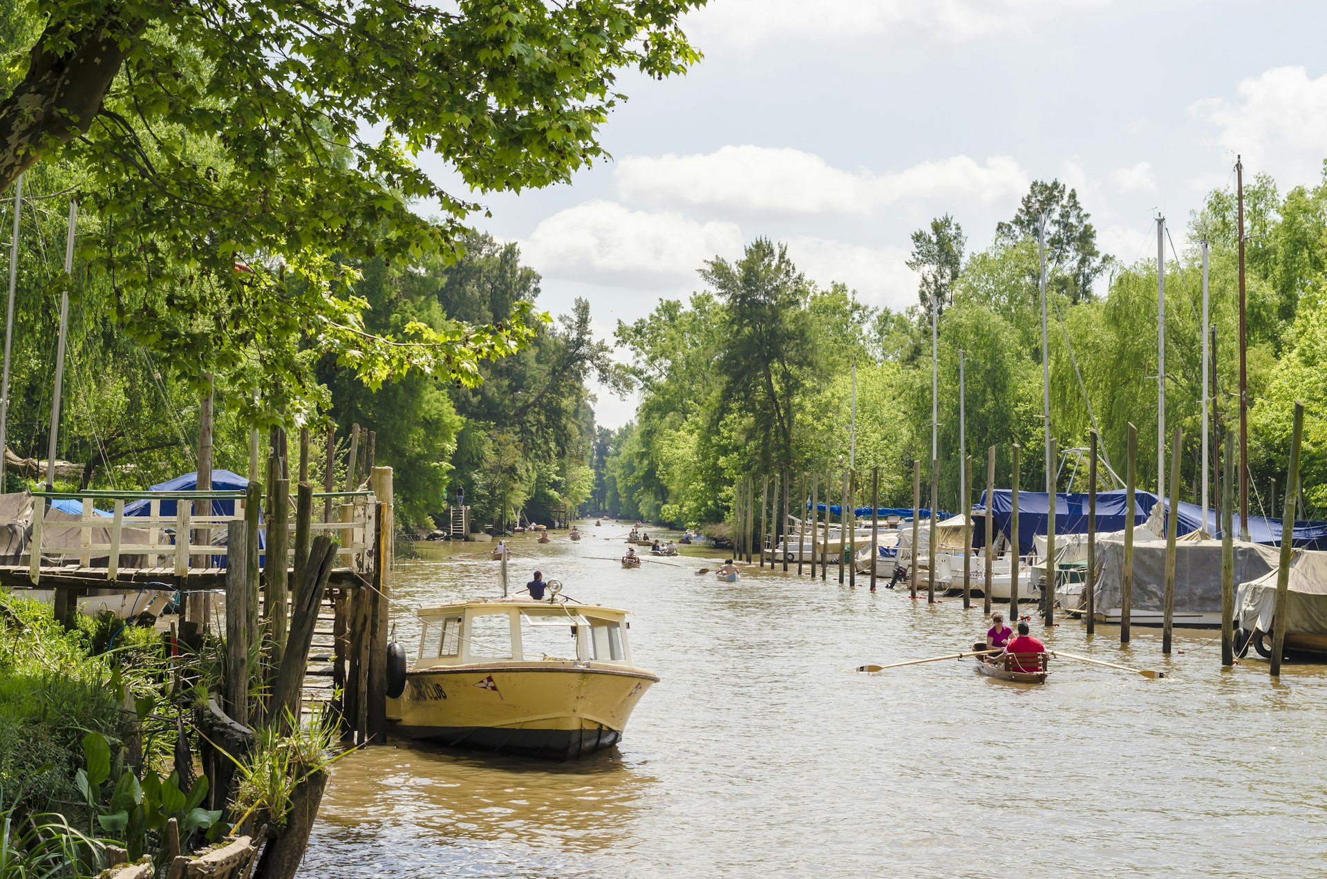 A canal lined with palm trees. A small row boat passed with two people on board