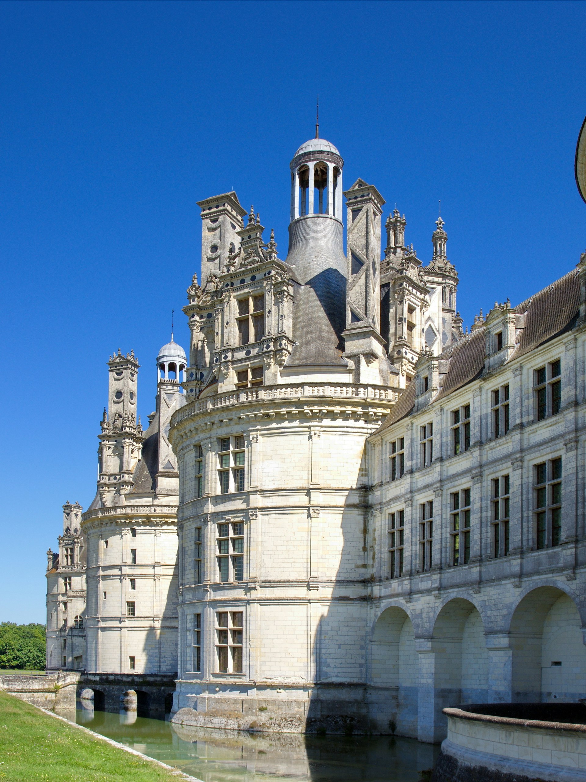 Huge white turrets rise from white walls with manicured lawns beneath 