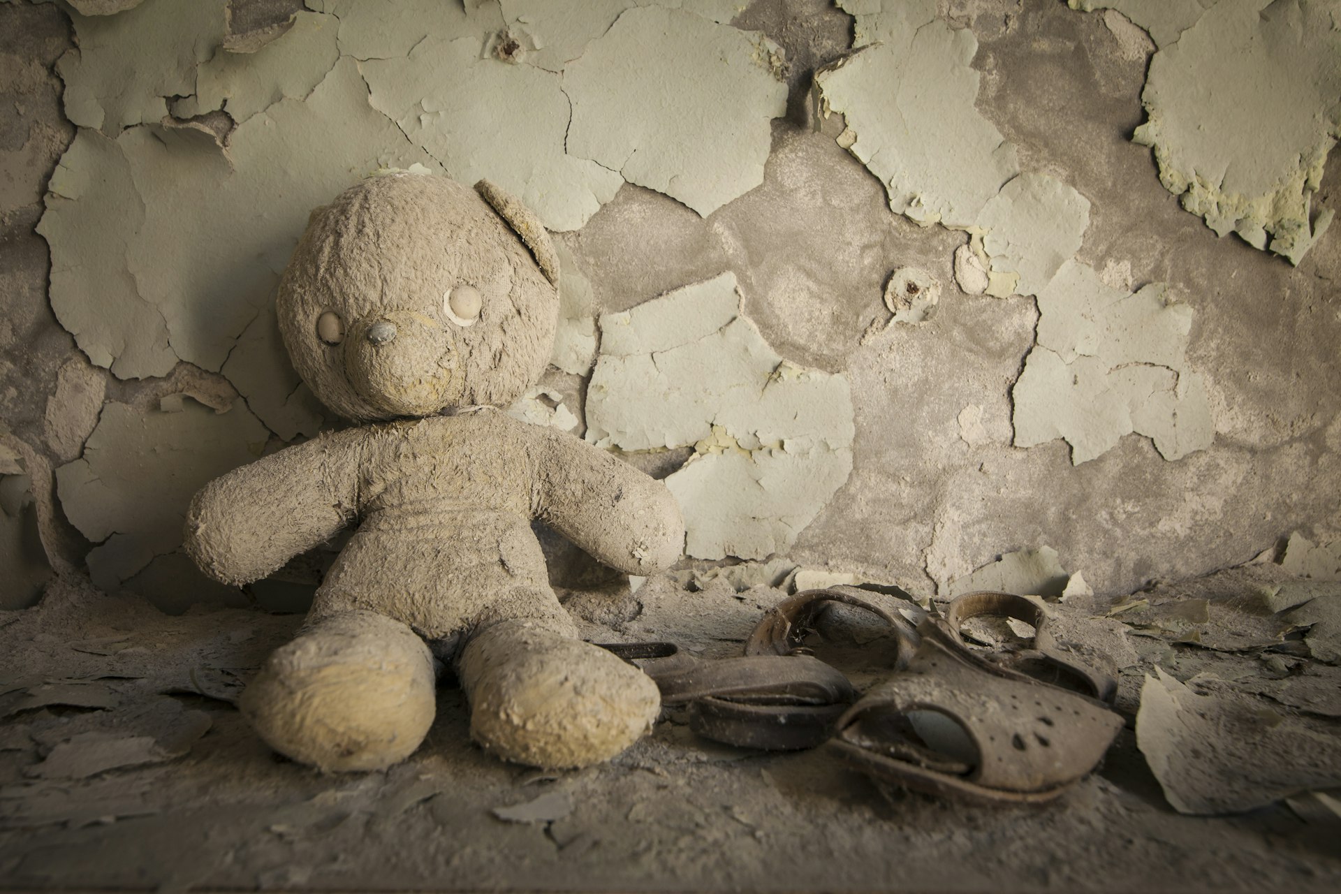 Old white teddy bear in an abandoned kindergarten