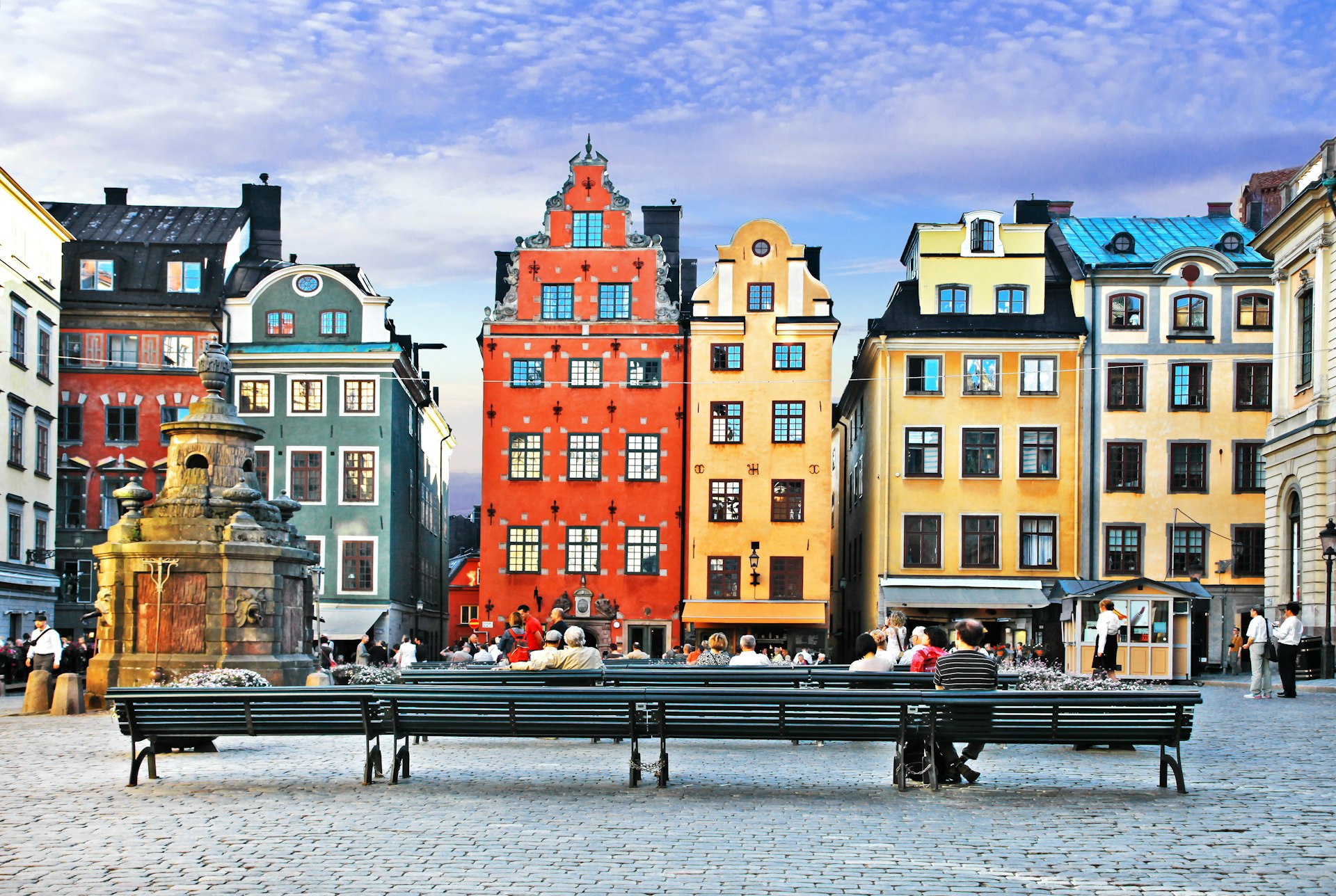 Grand buildings in yellow and orange pastels line an old town square