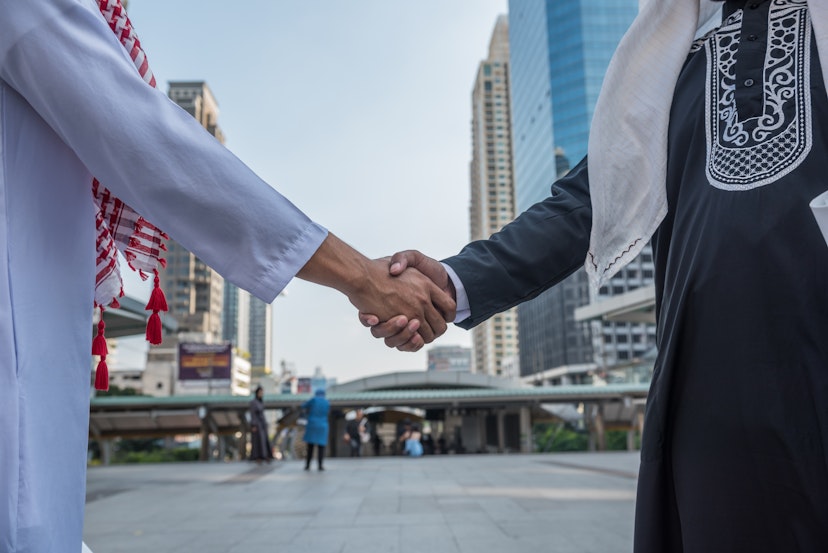 Arabian business partners shaking hands in a Saudi Arabian city.