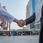 Arabian business partners shaking hands in a Saudi Arabian city.