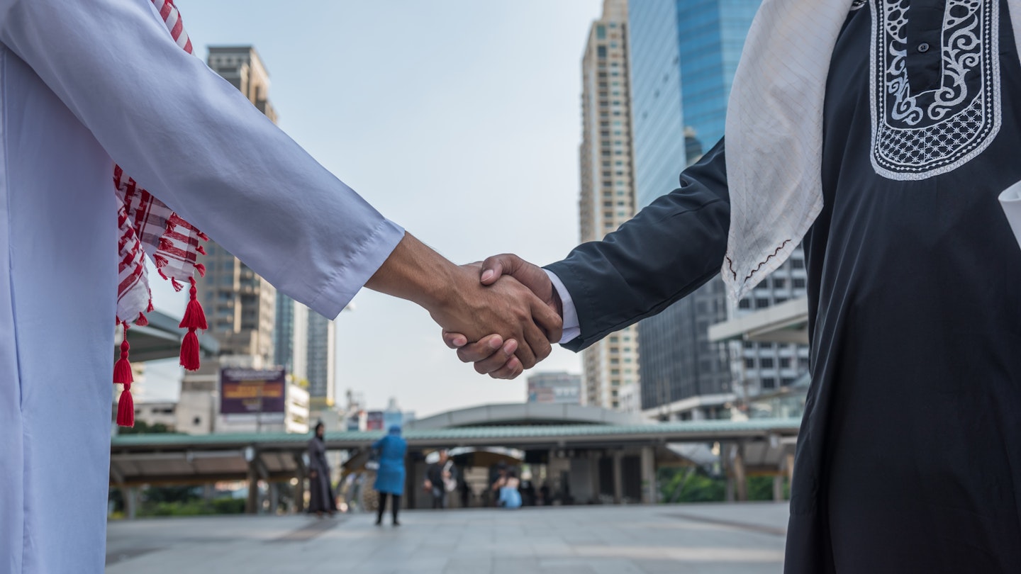 Arabian business partners shaking hands in a Saudi Arabian city.