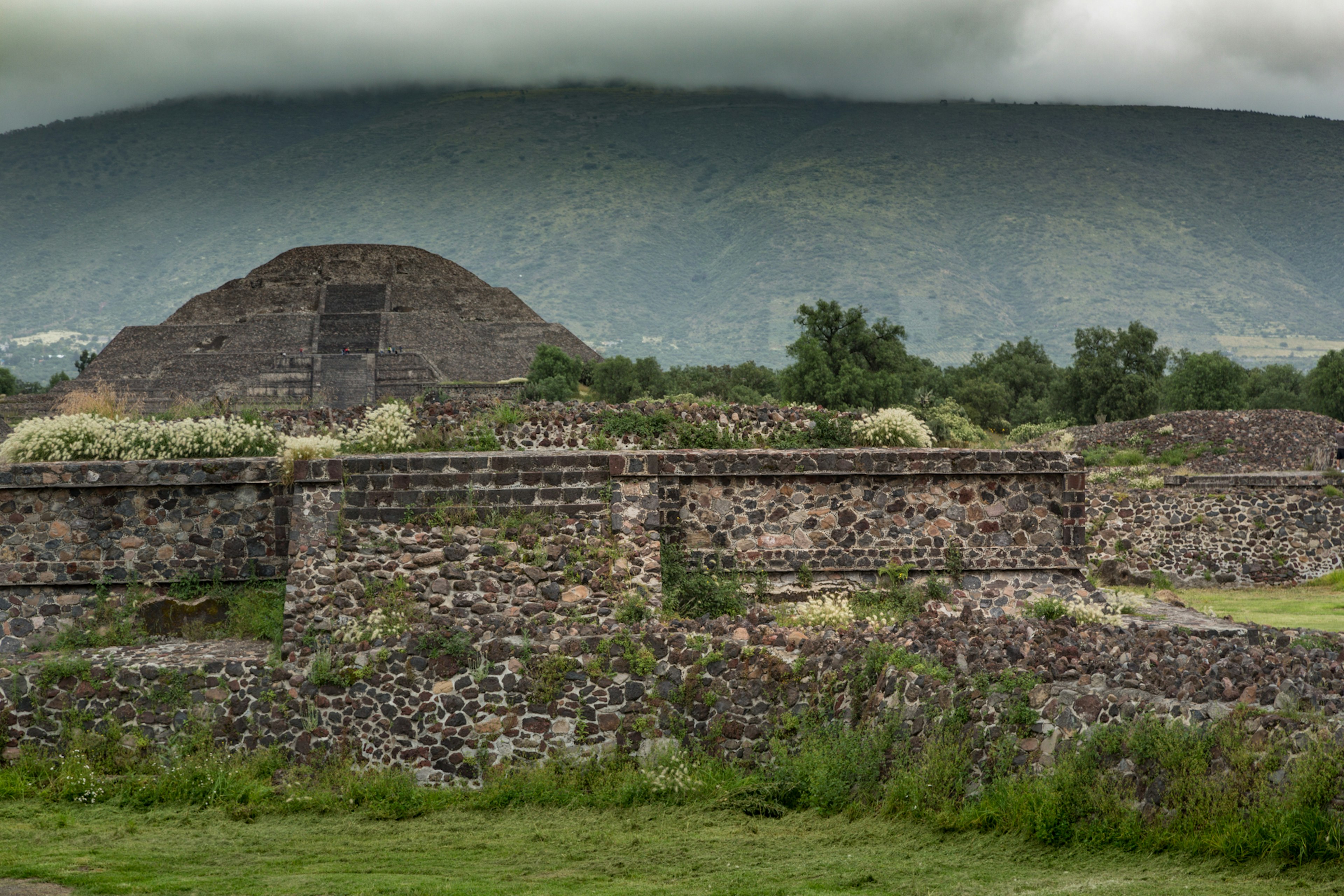 A stone pyramid with cloud-covered hillsides in the background