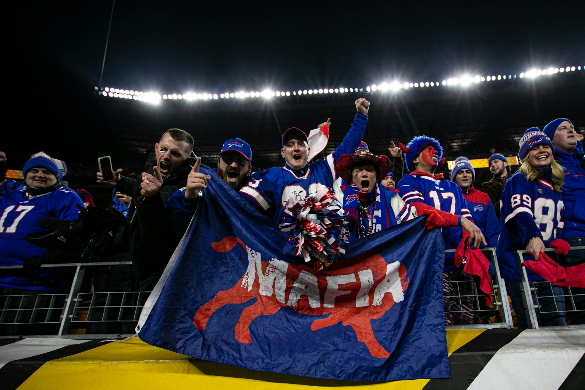 Bills Mafia fans hold a flag that says "mafia" and cheer during the NFL football game