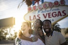Three friends smile and laugh Las Vegas sign in Las Vegas, Nevada, USA.
