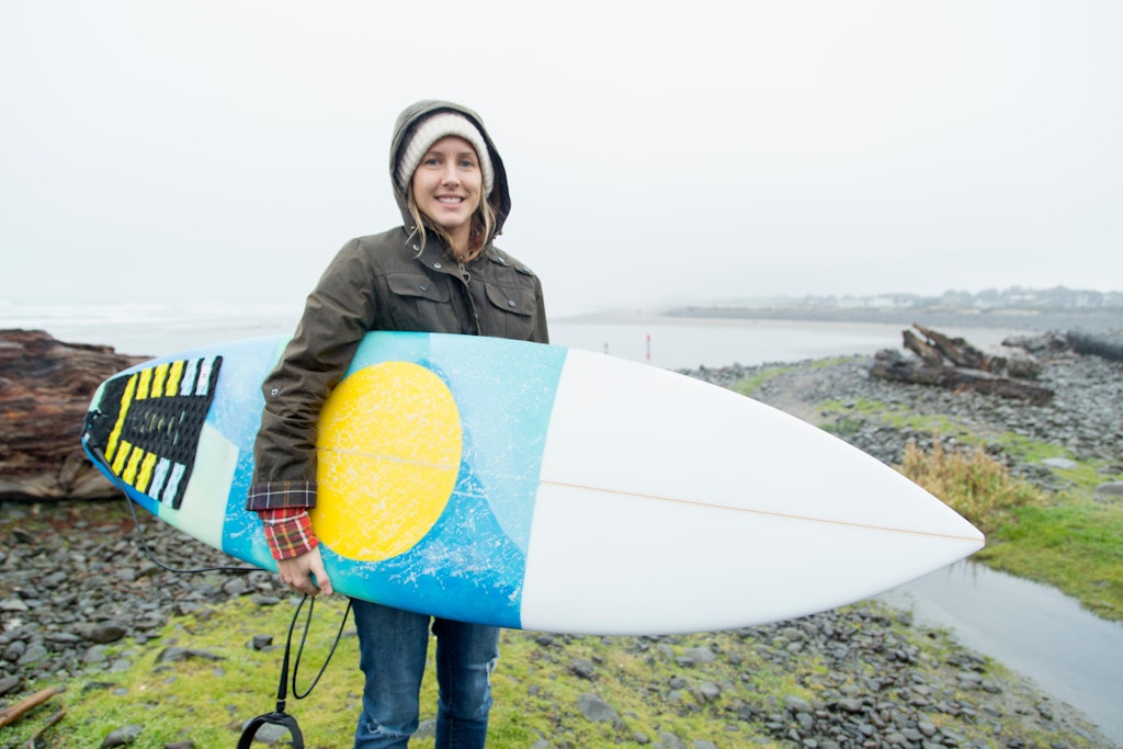 Portrait of female surfer carrying surfboard at coast, Seaside, Oregon, USA