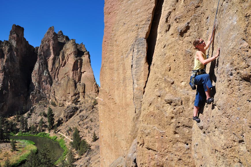 A woman ascends a cliff at Smith Rock State Park