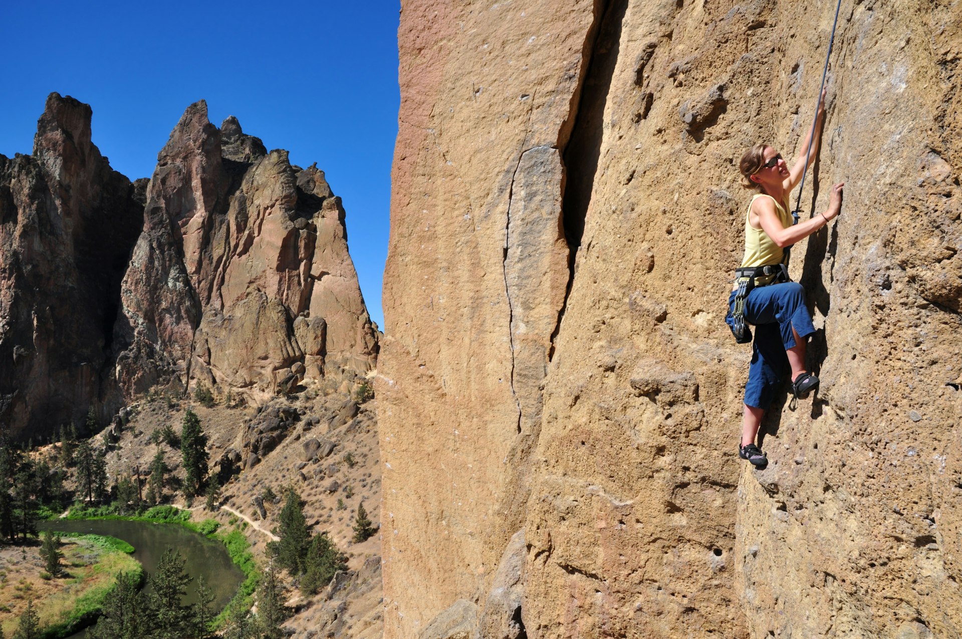 A female rock climber ascends a cliff at Smith Rock State Park
