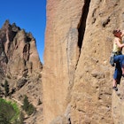 A female rock climber ascends a cliff at Smith Rock State Park.