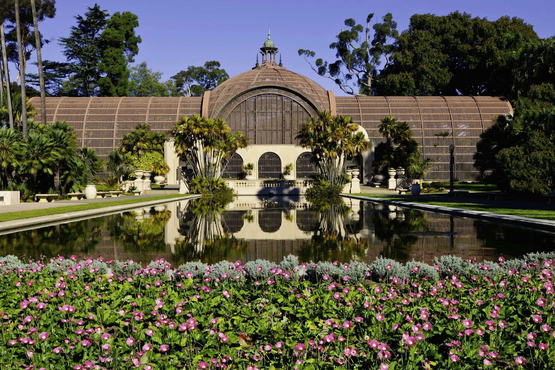 The Botanical Building in Balboa Park, San Diego reflects into a lake surrounded by flowers