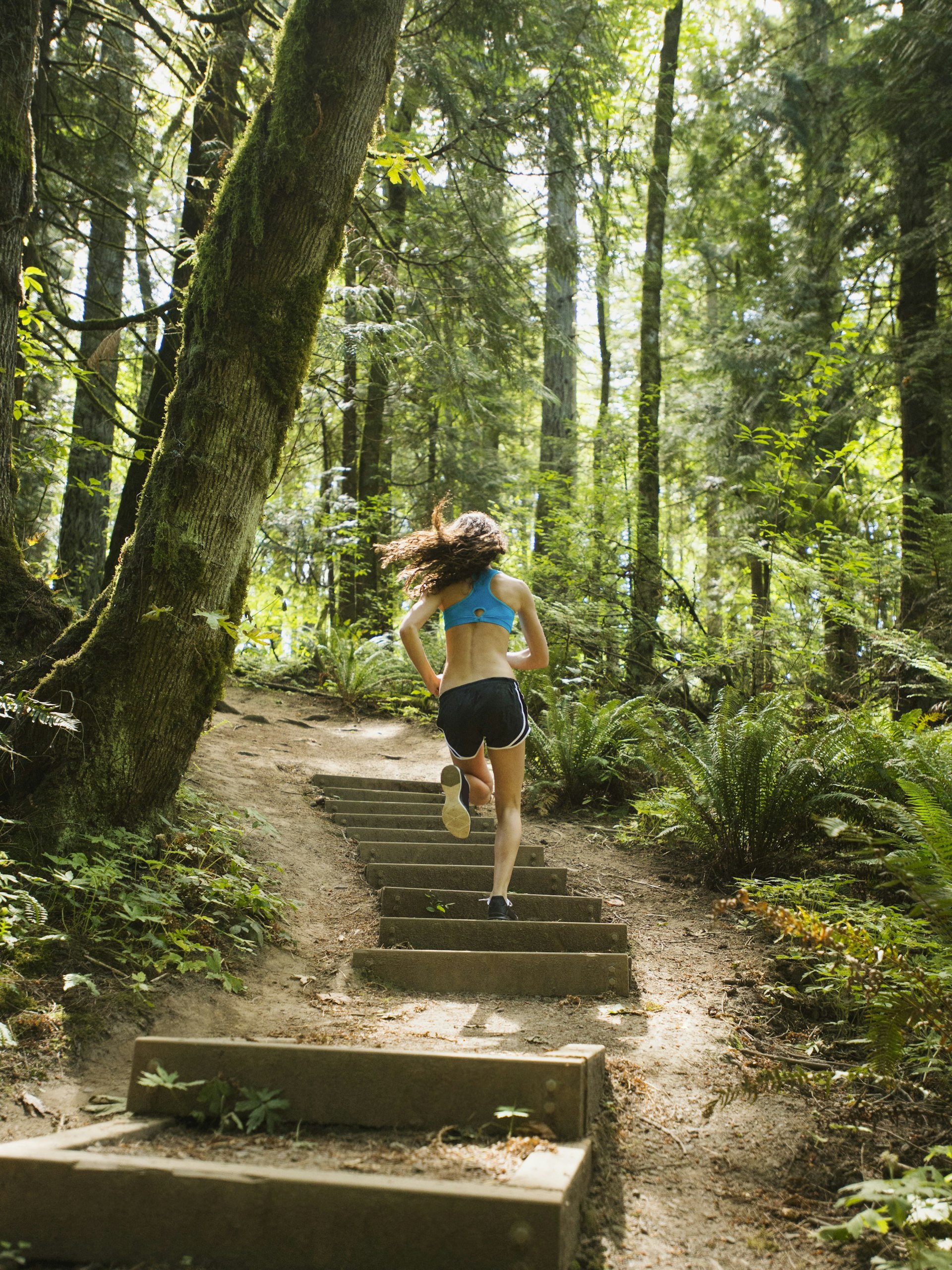 USA, Oregon, Portland, Rear view of young woman jogging in forest