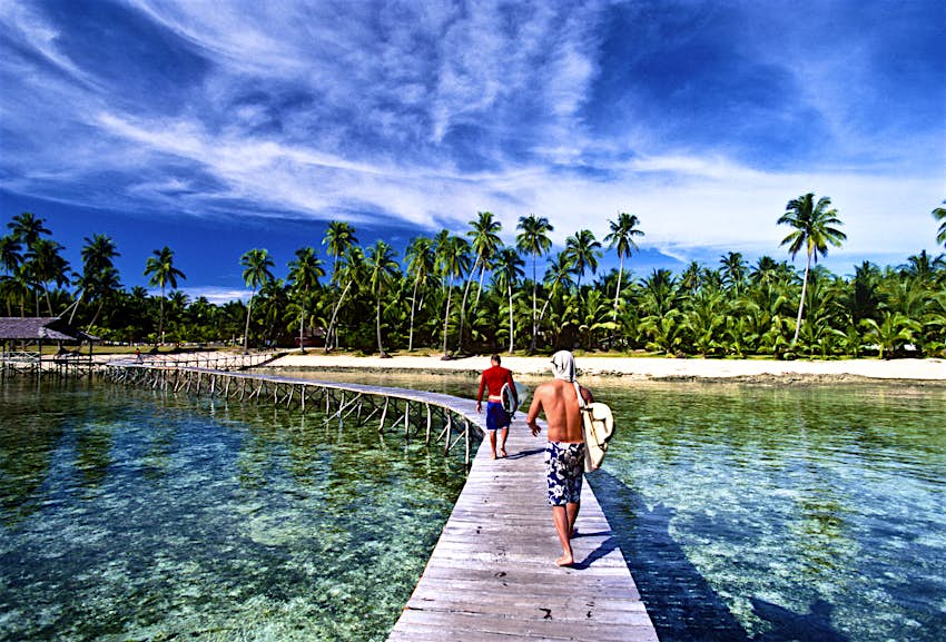 Be Adventurous! Two surfers walk along a wooden pier on Siargao Island, the Philippines