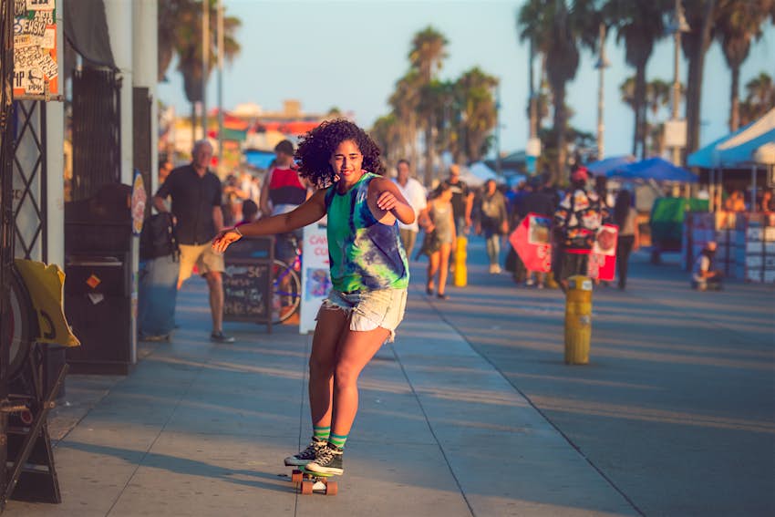 A young woman having fun skateboarding on the Venice Beach boardwalk